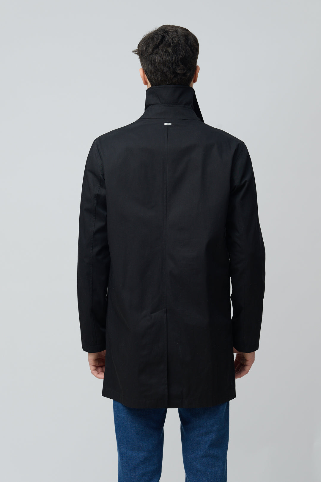 Homme portant un impermeable en gabardine de coton, dos visible, style élégant et fonctionnel, Herno – Officina Tessile.