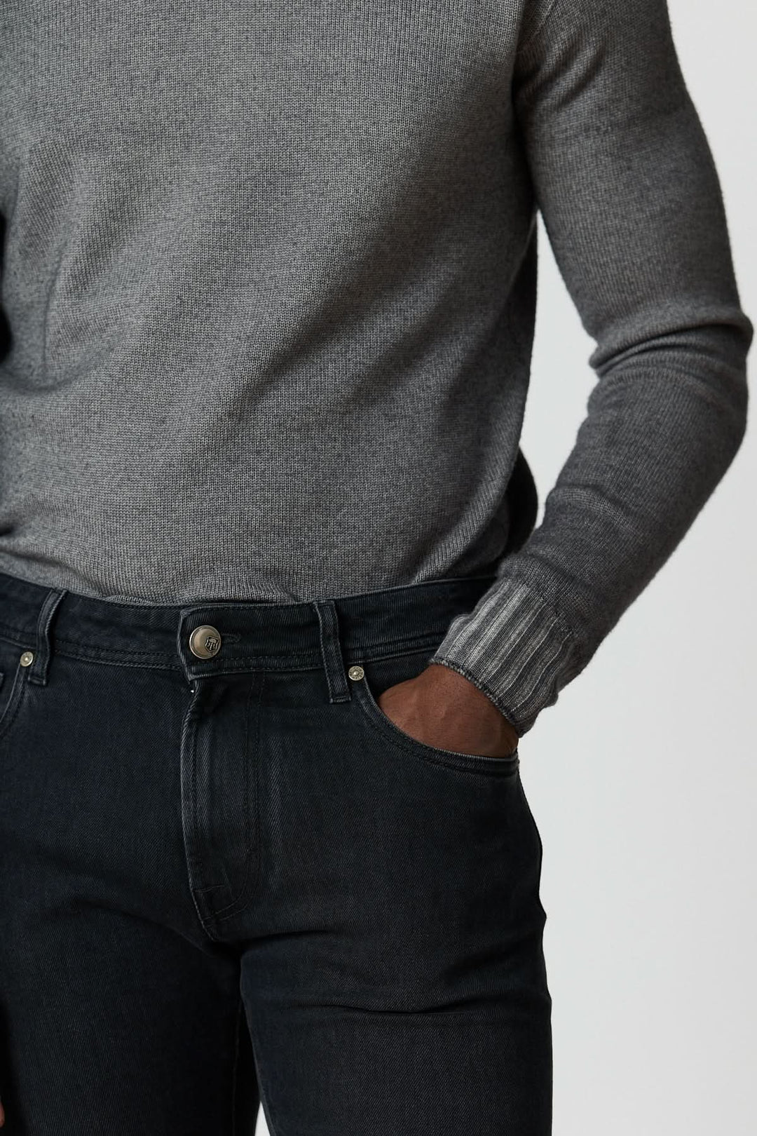 Jean 5 poches en denim stretch gris foncé ajusté pour un look moderne et confortable, porté avec un pull gris.