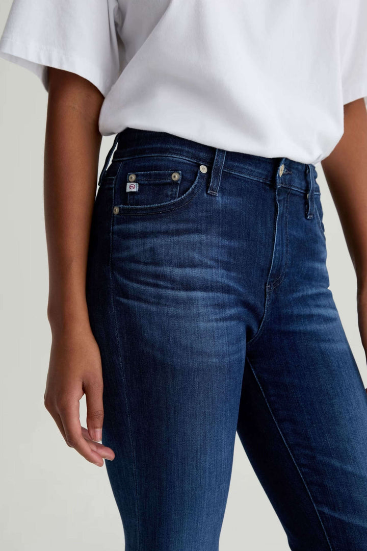 Jean ajusté à taille mi-haute en denim extensible, vue de face, porté avec une blouse blanche