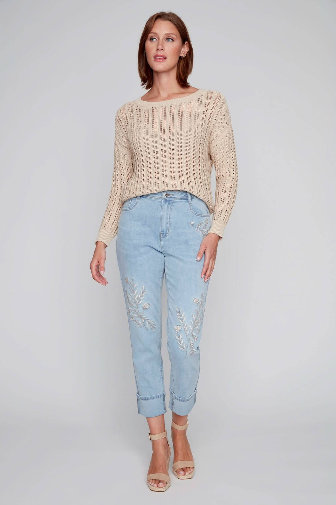 Jean à jambe droite avec broderies florales, porté avec un pull crème, parfait pour un look estival.