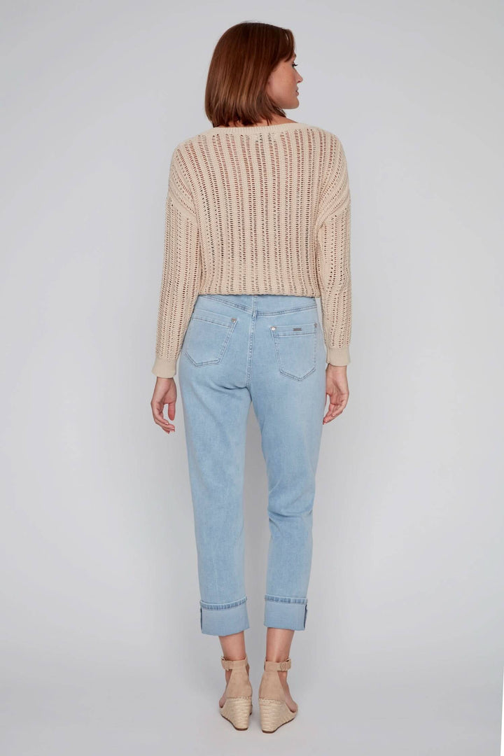 Femme de dos portant un pull beige et un jean décontracté bleu clair avec revers, look estival.