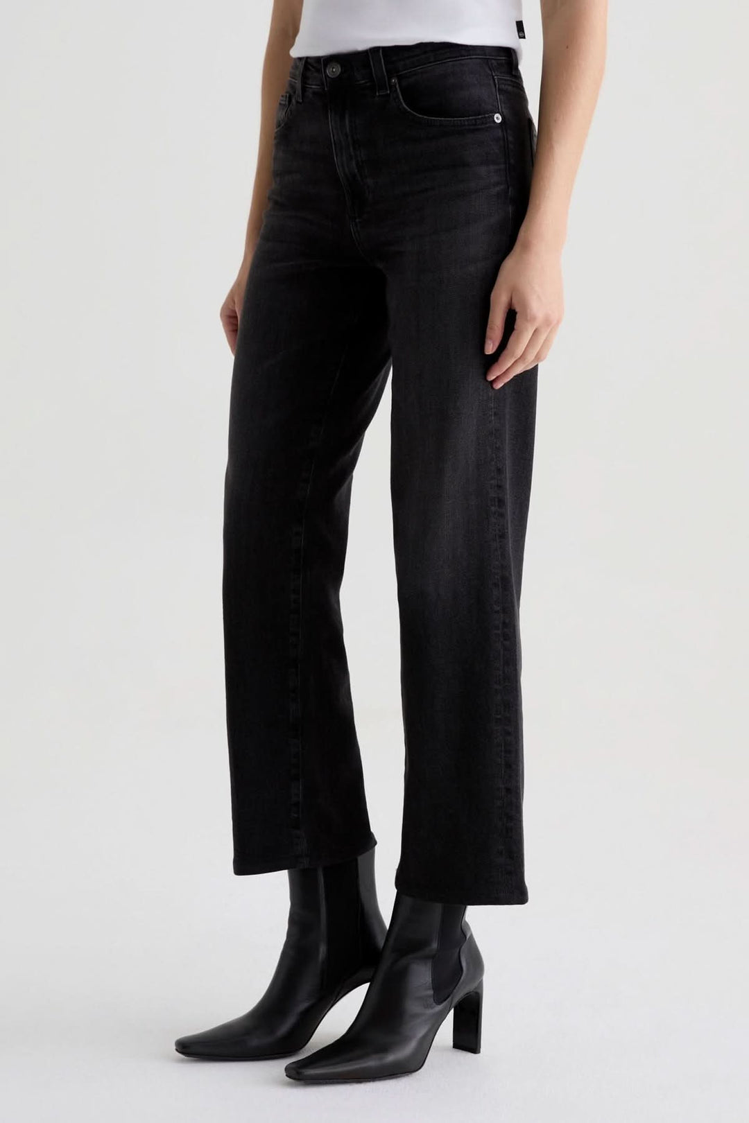 Jean à coupe droite en denim noir délavé, moderne et élégant, porté avec des bottillons.