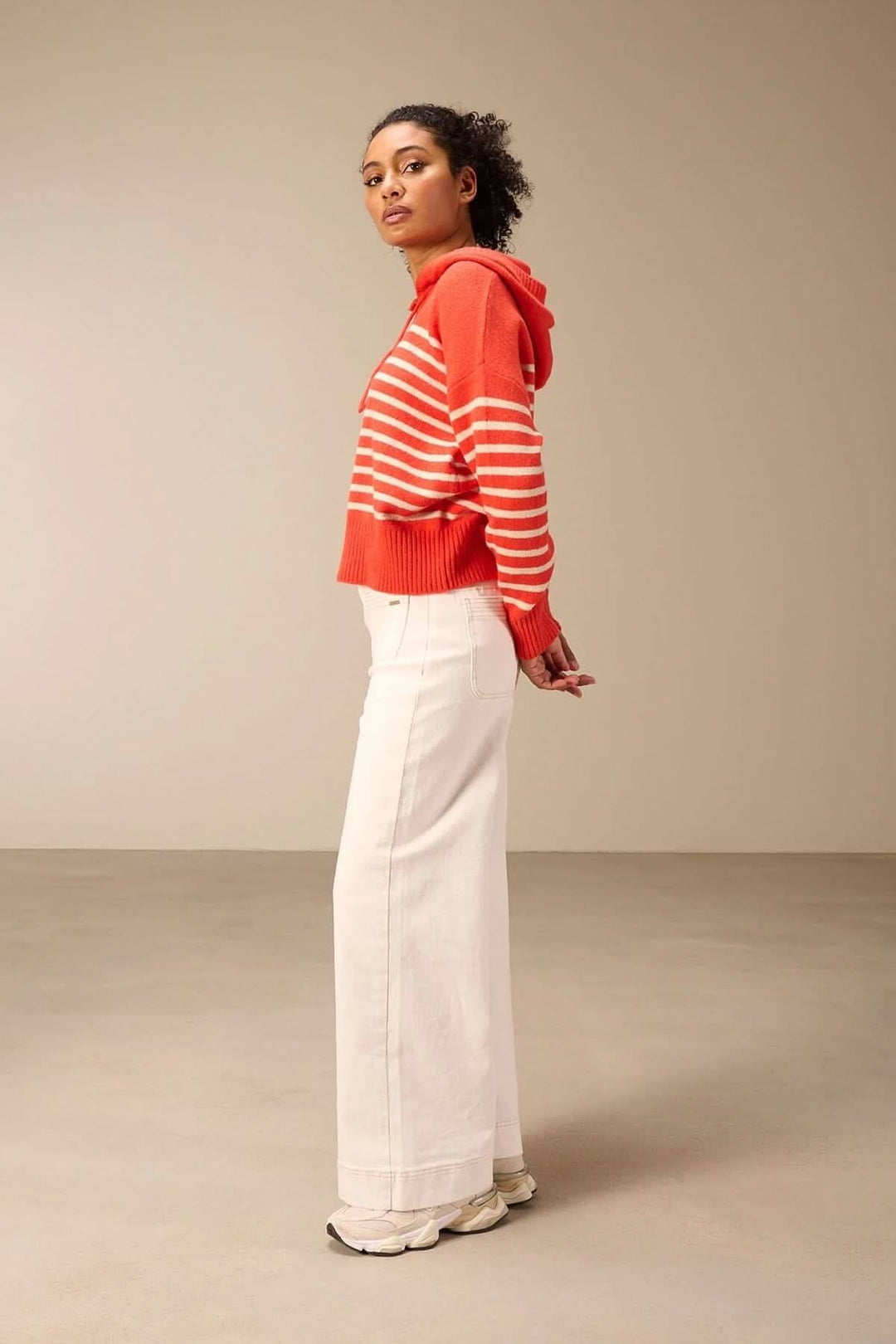 Femme portant un jean jambe large blanc avec un pull rayé rouge pour un look rétro et moderne, confort et style au quotidien.