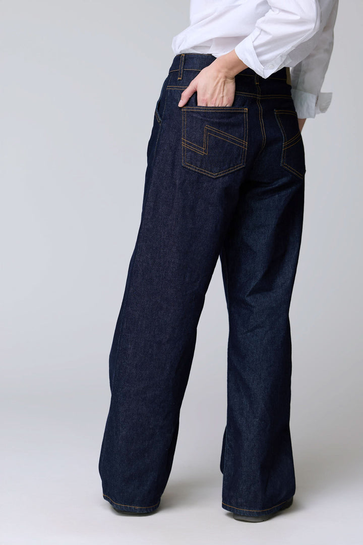 Jean à jambe large en denim brut avec coupe ample et surpiqûres contrastantes, offrant une allure vintage et confort durable.
