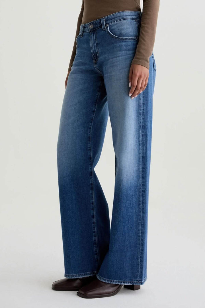 Jean à jambe large, délavage moyen, offrant confort et silhouette fluide. Décris moi le produit en français pour plus de détails.