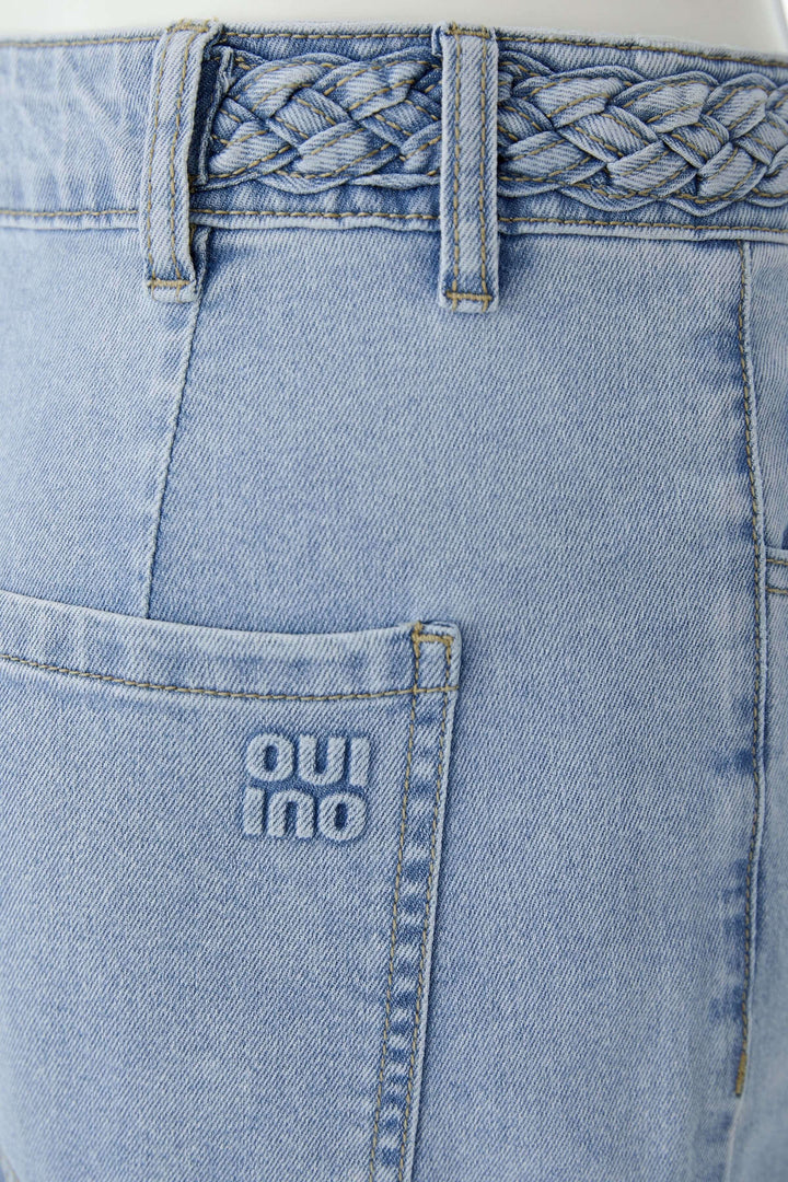 Jean à jambe large avec taille tressée en denim bleu clair, détail de la taille avec tressage élégant.