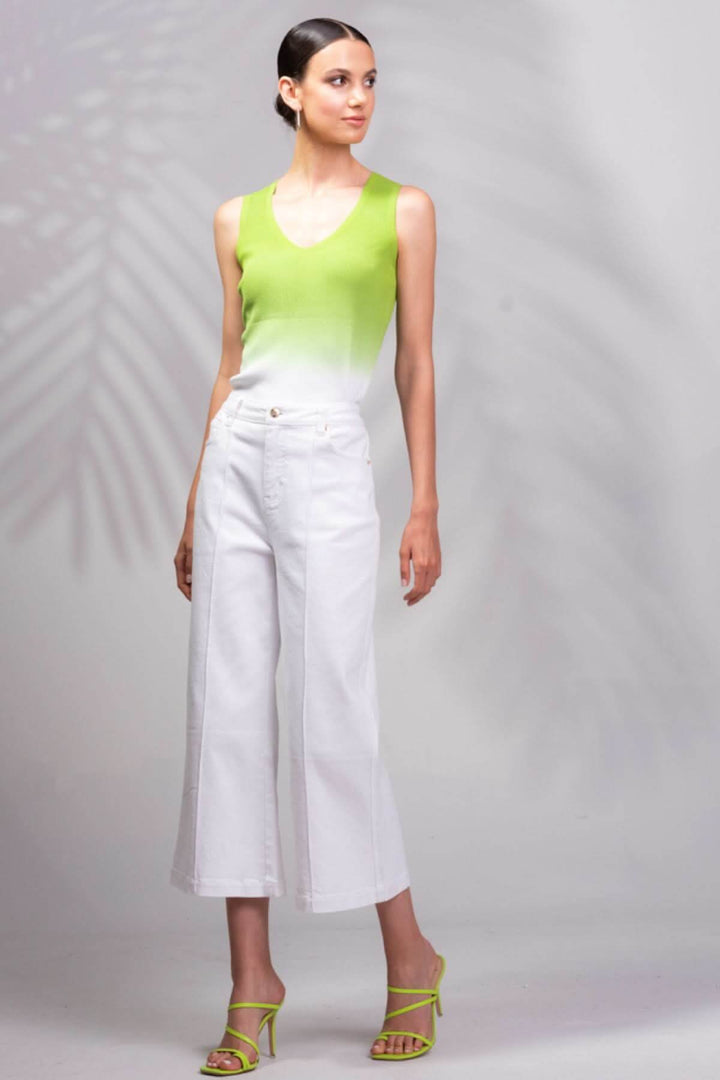 Femme en top vert et pantalons blancs, mettant en valeur un style moderne et élégant.