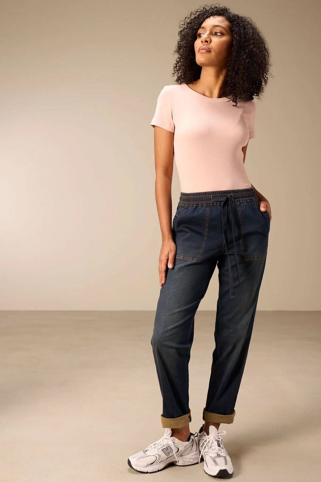 Femme portant un jeanjogging à taille élastique avec t-shirt rose, alliant confort et style décontracté moderne.