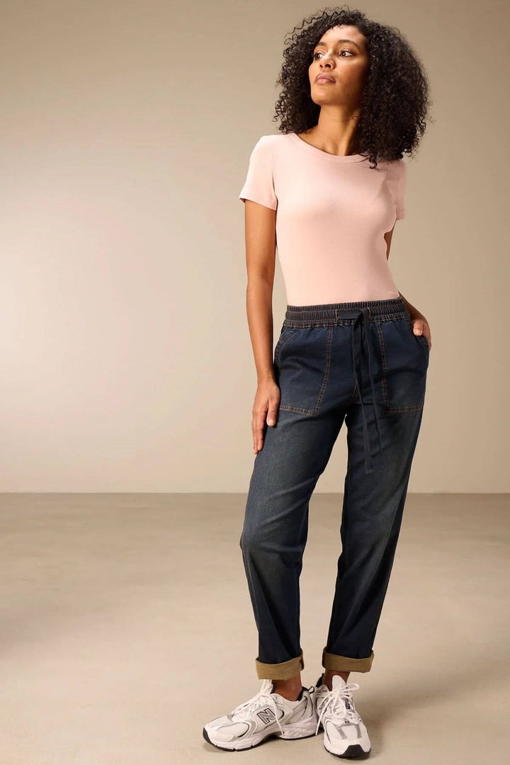 Femme portant un jeanjogging à taille élastique avec t-shirt rose, alliant confort et style décontracté moderne.