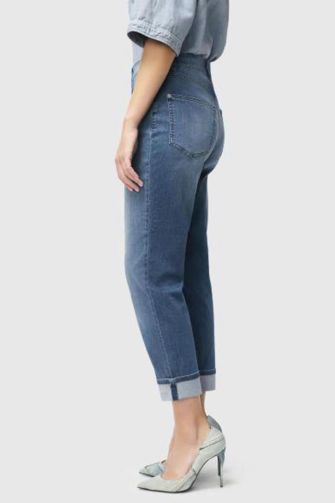 Feminine high-waisted jeans in light denim with rolled cuffs, paired with stylish heels, showcasing a classic yet contemporary look.