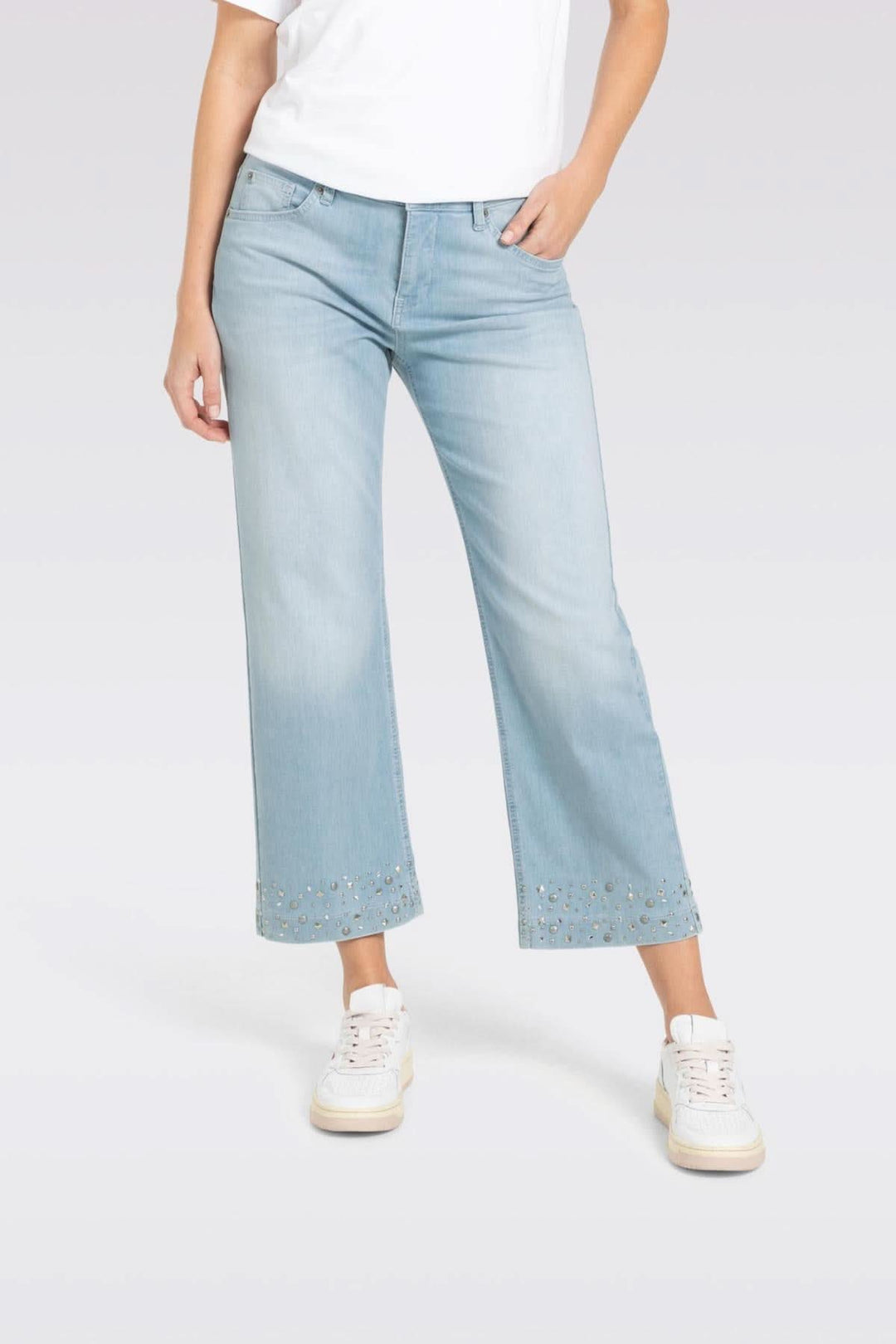 Jeans culotte en denim léger, coupe large et jambe raccourcie, avec studs brillants au bas, portés avec des baskets.