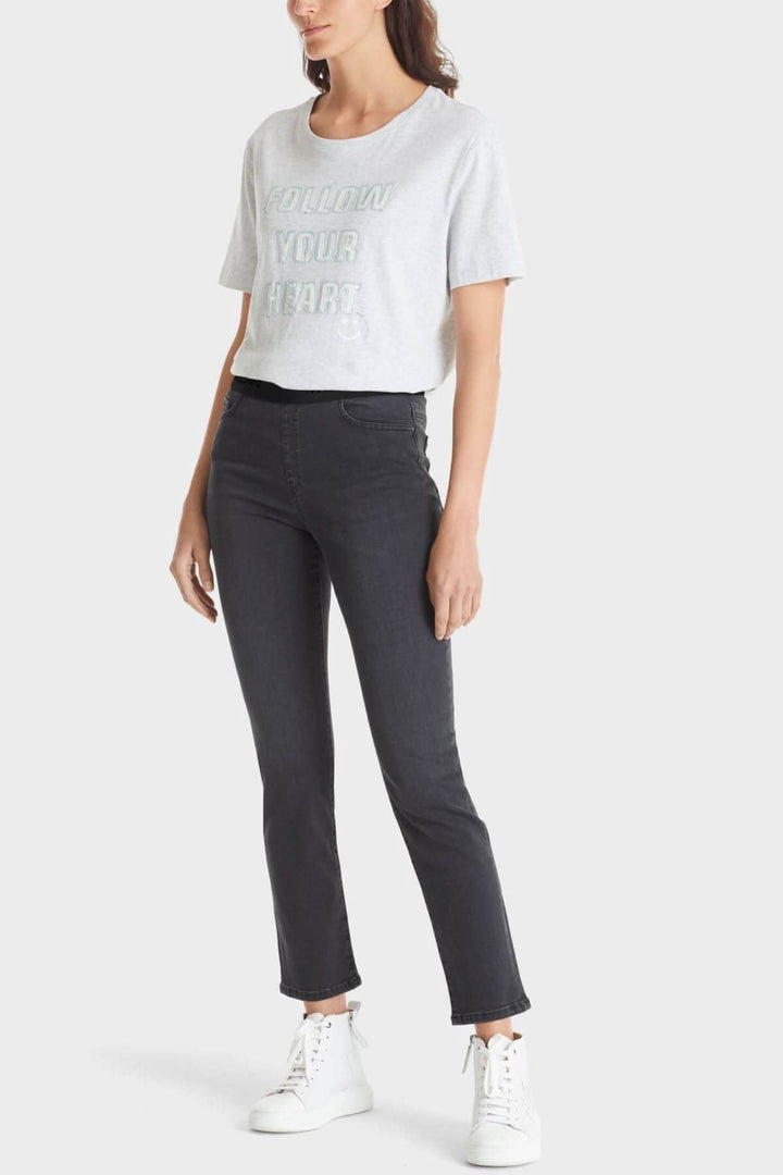 Femme en jeans anthracite slim avec ceinture élastique et t-shirt gris, look moderne et confortable.