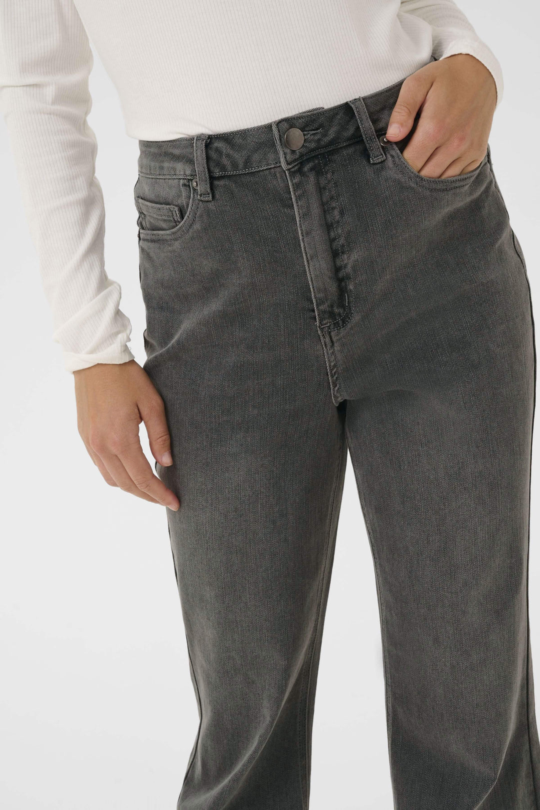 Jean à jambe évasée, taille haute, finition délavée, style rétro, porté avec un chandail ajusté.