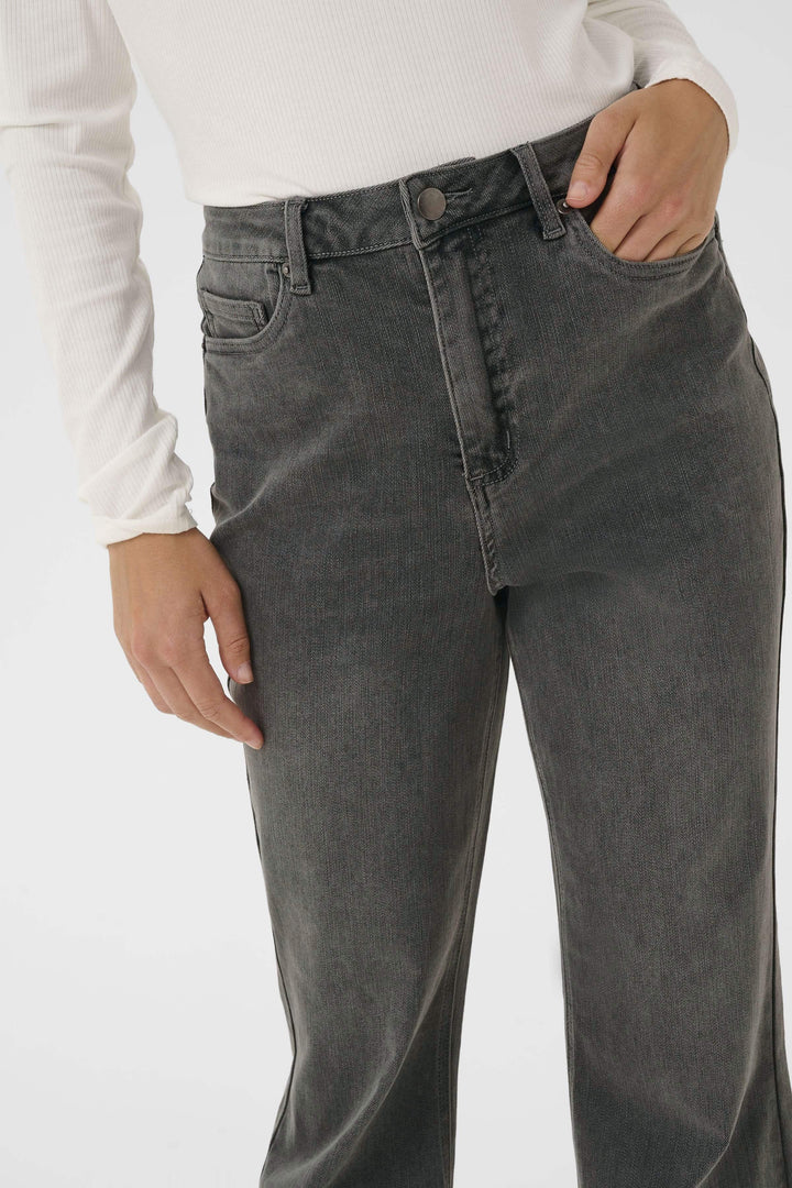 Jean à jambe évasée, taille haute, finition délavée, style rétro, porté avec un chandail ajusté.