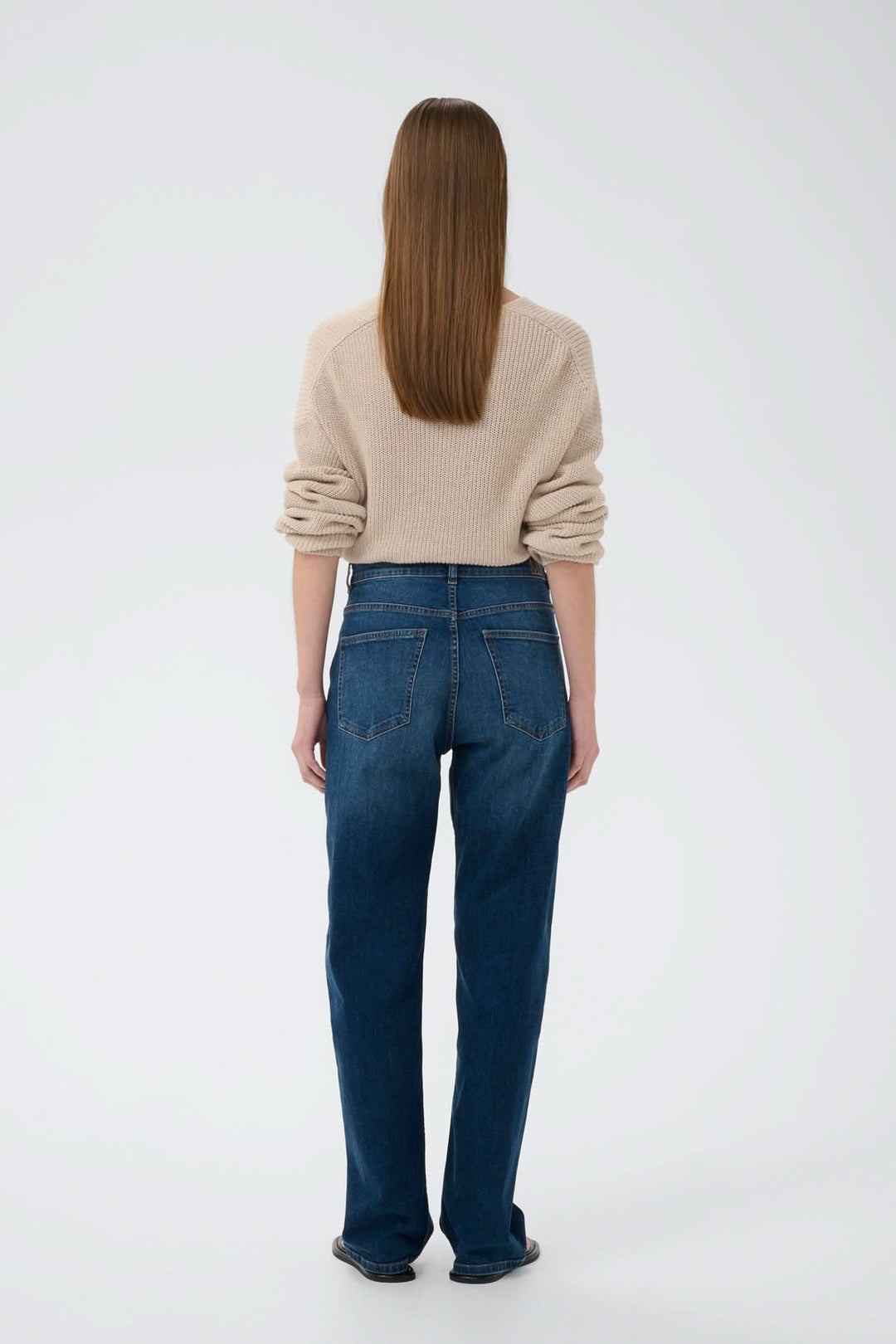 Femme portant Jeans décontractée Darlina, en denim légèrement délavé, vue de dos, coupe droite, poches arrière, tenue moderne et casual.