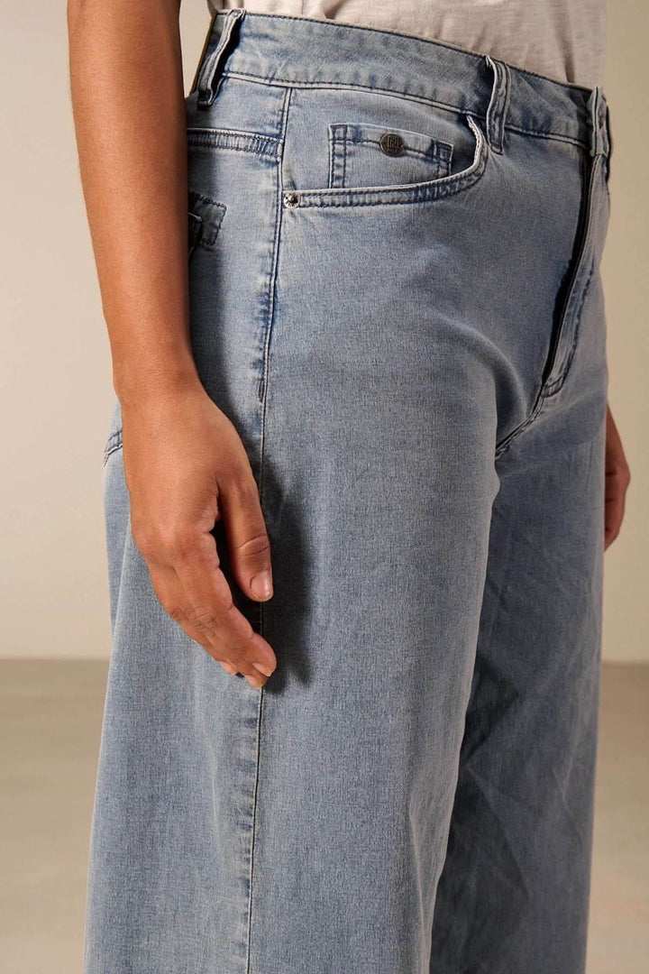 Jeans jambe large avec coupe évasée et taille haute, vue de côté pour mettre en valeur la silhouette rétro et contemporaine.