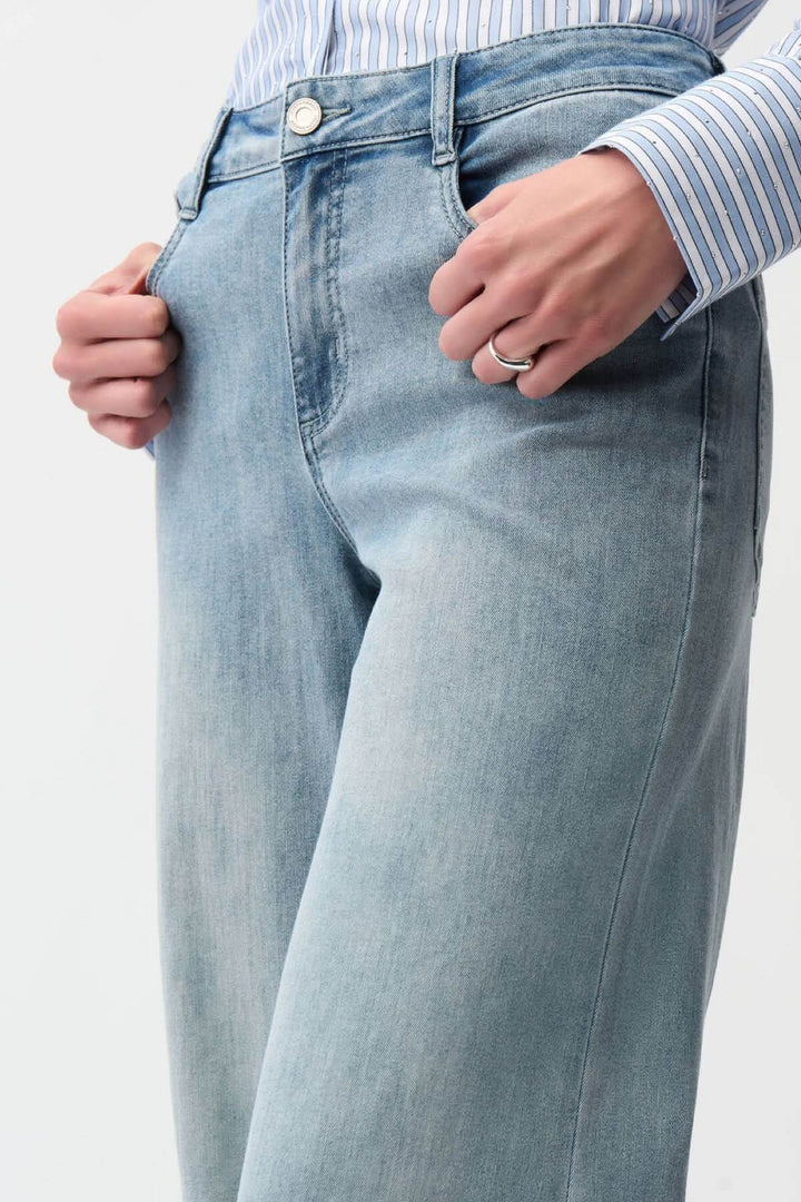 Jeans à jambe large taille haute en denim bleu clair porté avec chemise rayée, offrant confort et style moderne