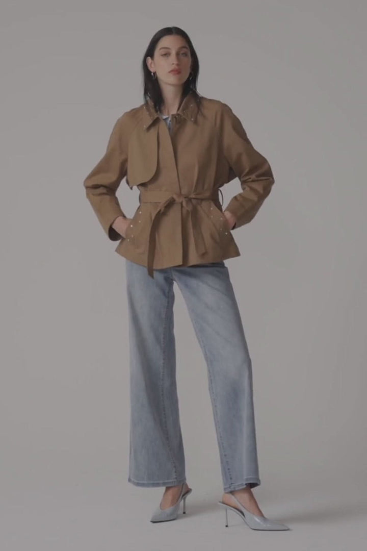 Femme portant des jeans à jambe large taille haute avec une veste marron et des talons argentés, posant avec confiance.