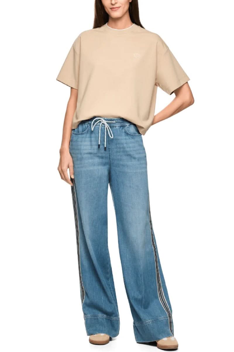 Jeans large à bandes contrastantes avec taille élastique et coupe fluide, porté avec un t-shirt beige, vue complète.