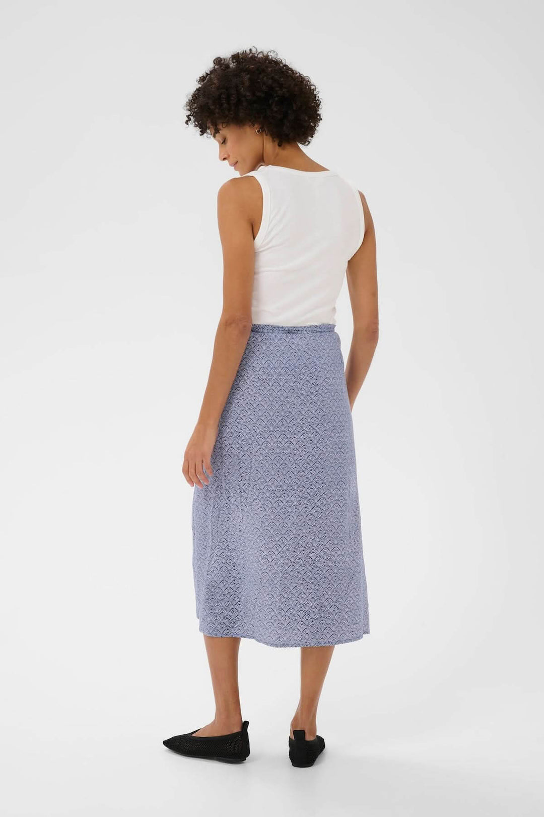 Femme portant la Jupe Arielle midi avec imprimé délicat et taille ajustable, vue arrière.