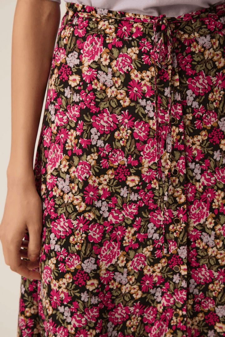 Jupe Elizette longue fluide à taille nouée avec imprimé floral coloré et tissu léger, parfaite pour un style confortable et élégant.