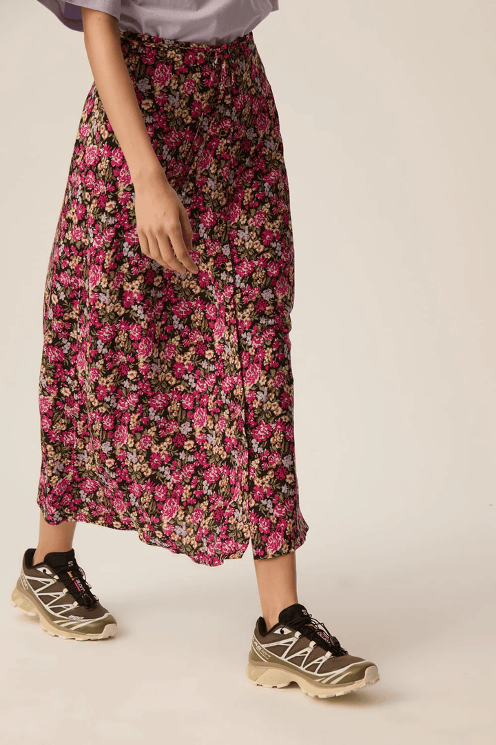 Jupe Elizette longue fluide à taille nouée avec motif floral, illustrant une silhouette féminine et fluide. Décris moi le produit en français.