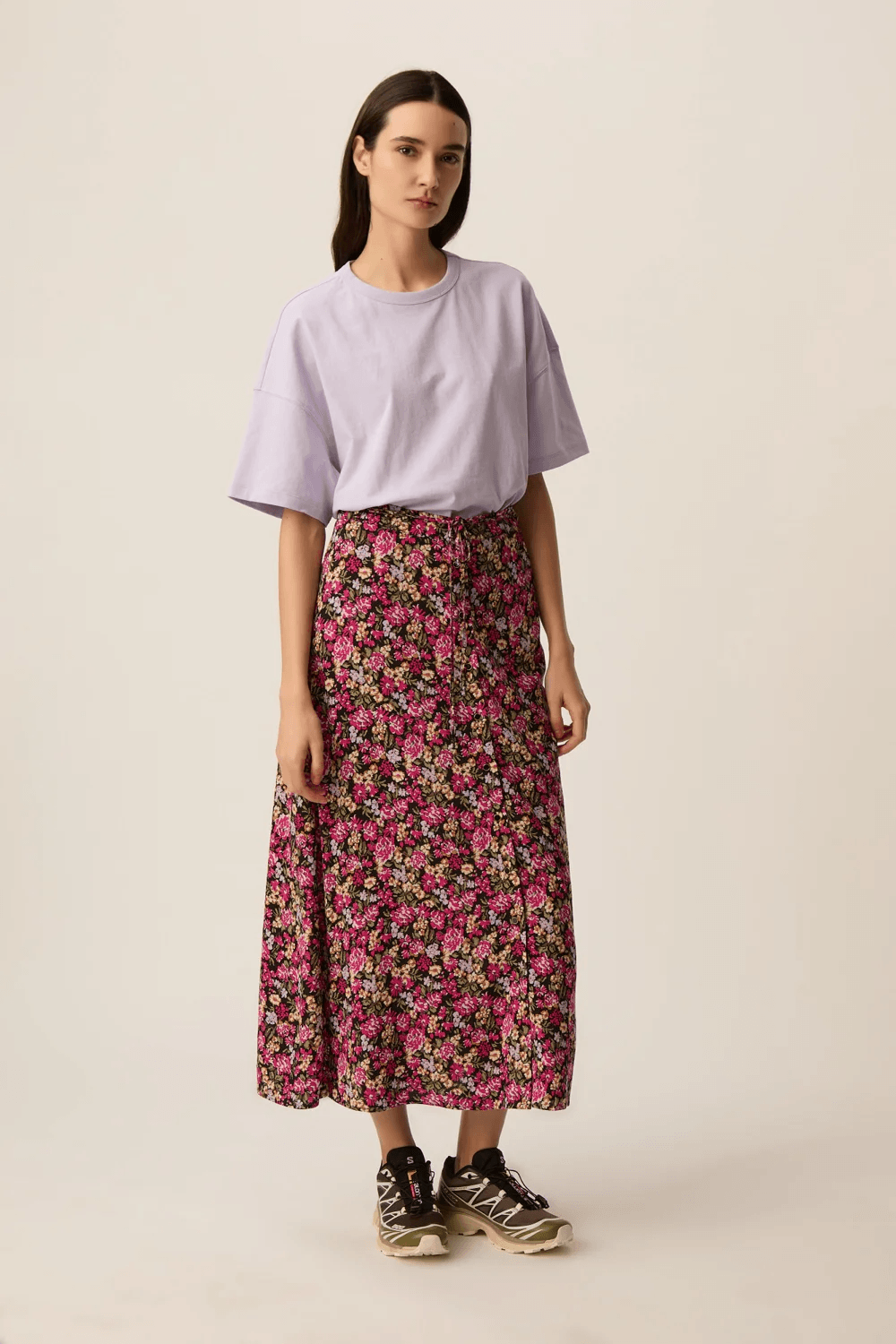 Femme portant la Jupe Elizette longue fluide à taille nouée avec motif floral, silhouette fluide et élégante.