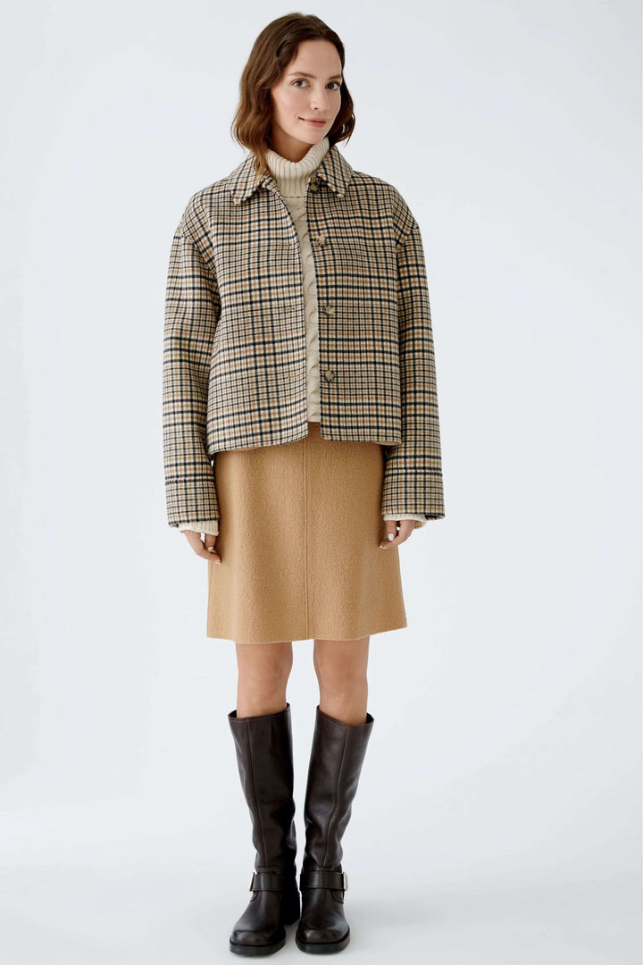 Jupe courte en lainage, taille haute avec veste à carreaux, pull col roulé et bottes hautes, look élégant et raffiné.