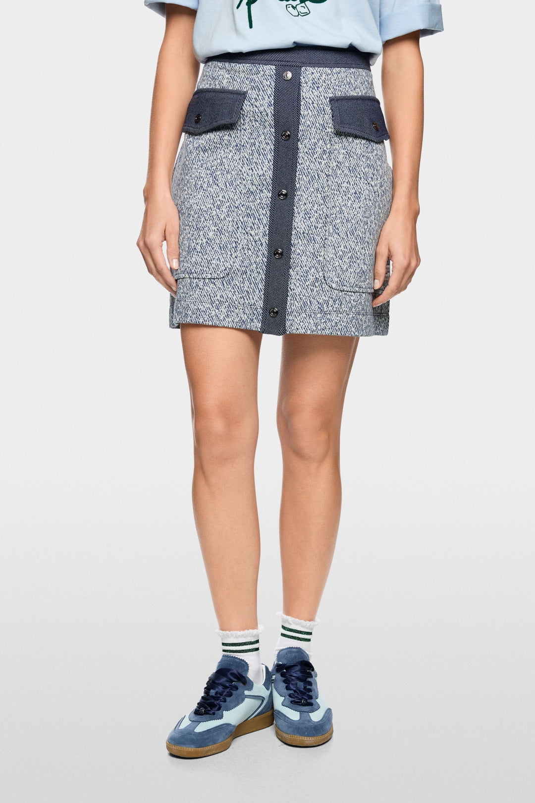 Jupe courte en viscose extensible avec fermeture boutonnée et poches à rabat, allure structurée et inspiration utilitaire moderne.