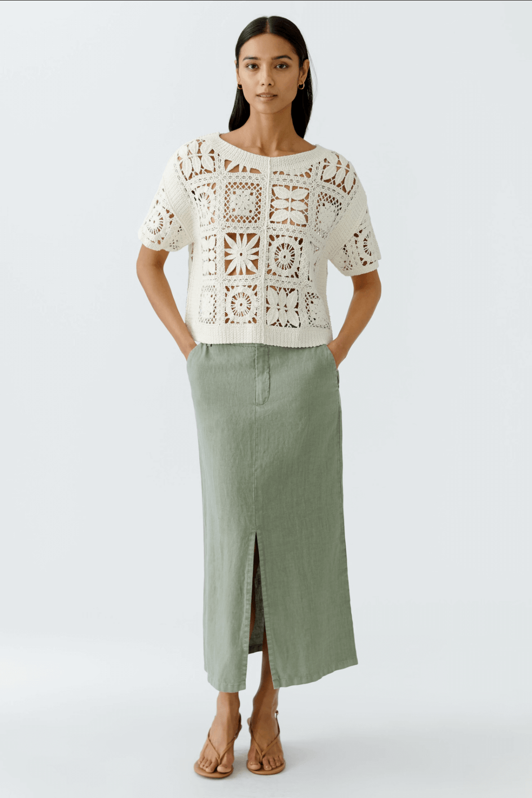 Femme portant une jupe longue en lin avec poches et fente, associée à un top en crochet blanc.