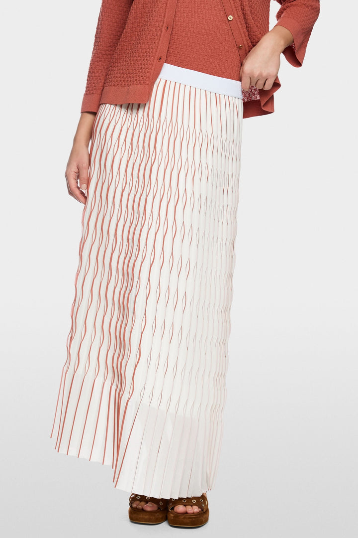 Femme portant une jupe longue plissée avec taille élastique pour un look élégant et féminin, idéale pour toutes occasions.