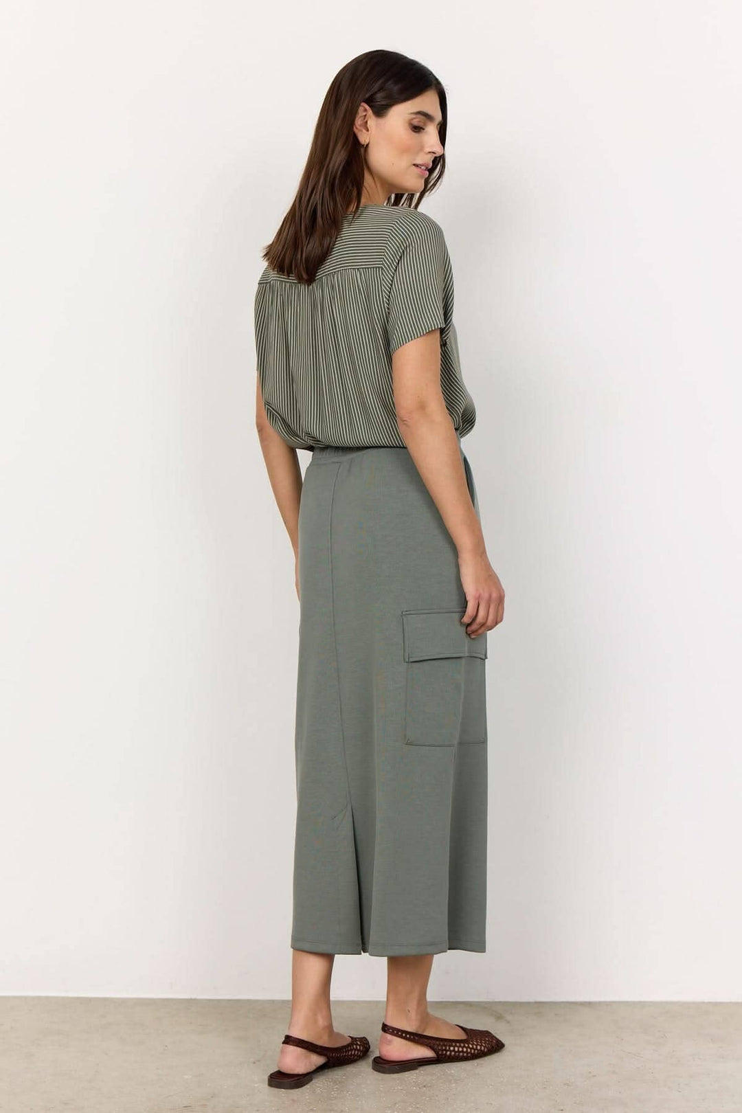 Femme portant une jupe longue souple en modal avec poches, vue arrière, style décontracté.
