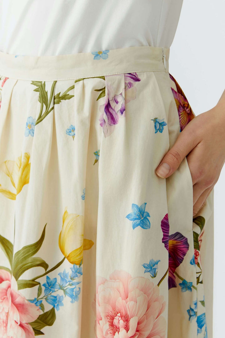 Jupe mi-longue imprimé de fleurs, détail de la taille structurée et coupe évasée avec motifs floraux élégants.