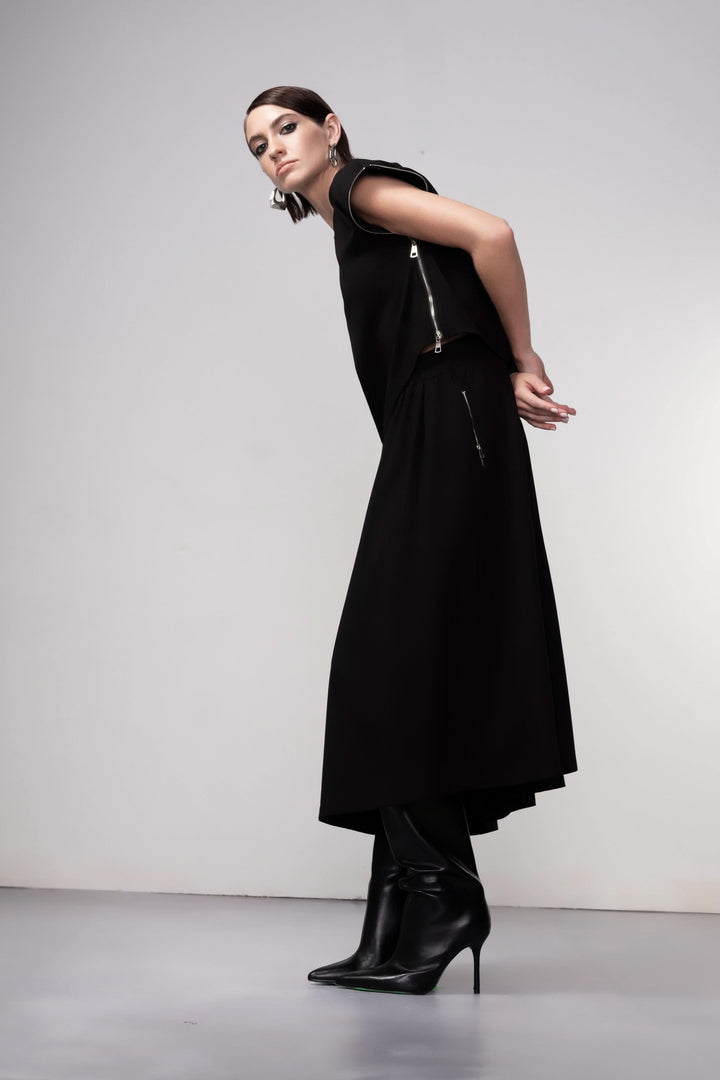 Modèle portant une jupe midi coupe fluide noire avec talons, accentuant le mouvement et l&