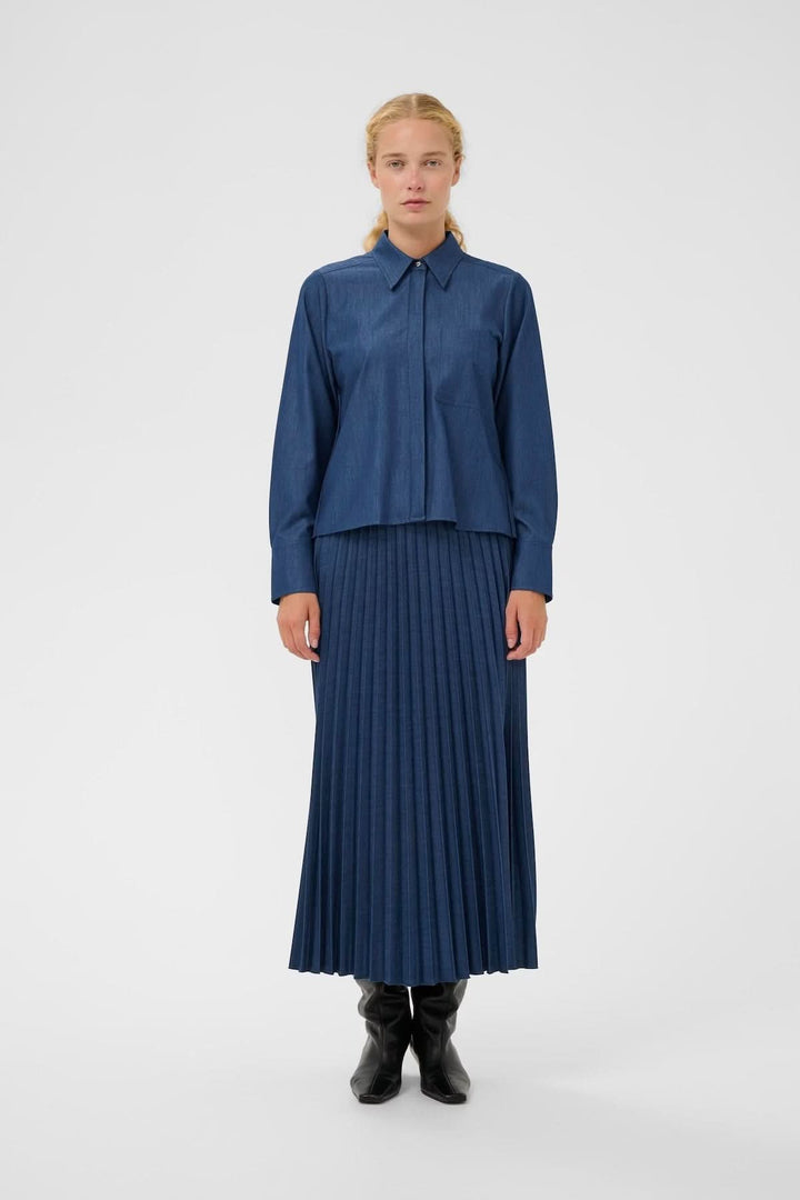 Jupe midi plissée Cherrie élégante et moderne avec effet denim, longueur mi-mollet pour un style fluide et féminin.