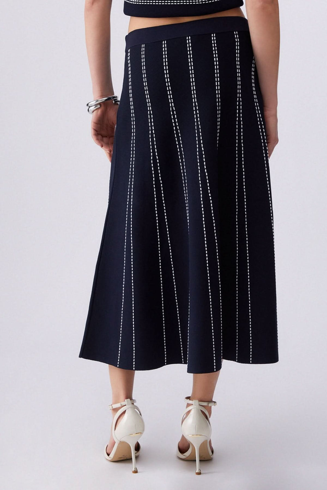 Jupe midi évasée à motif rayé avec taille confortable et coupe élégante, vue de dos, soulignant la liberté de mouvement raffinée.