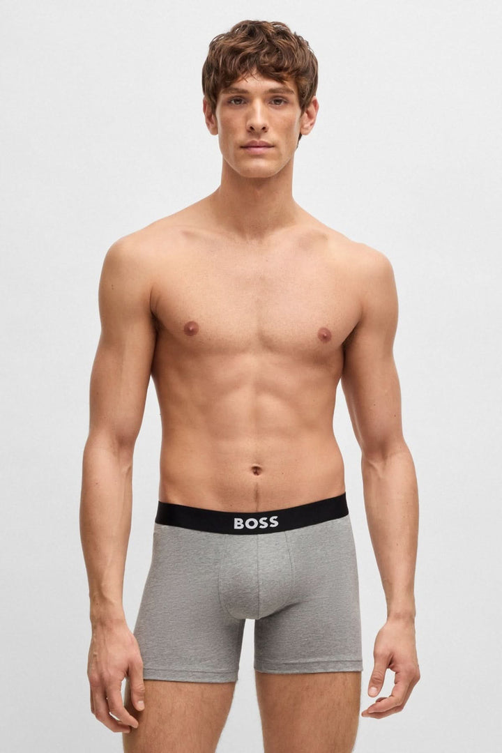 Homme en boxers longs gris avec ceinture logo BOSS, montrant confort et style moderne.