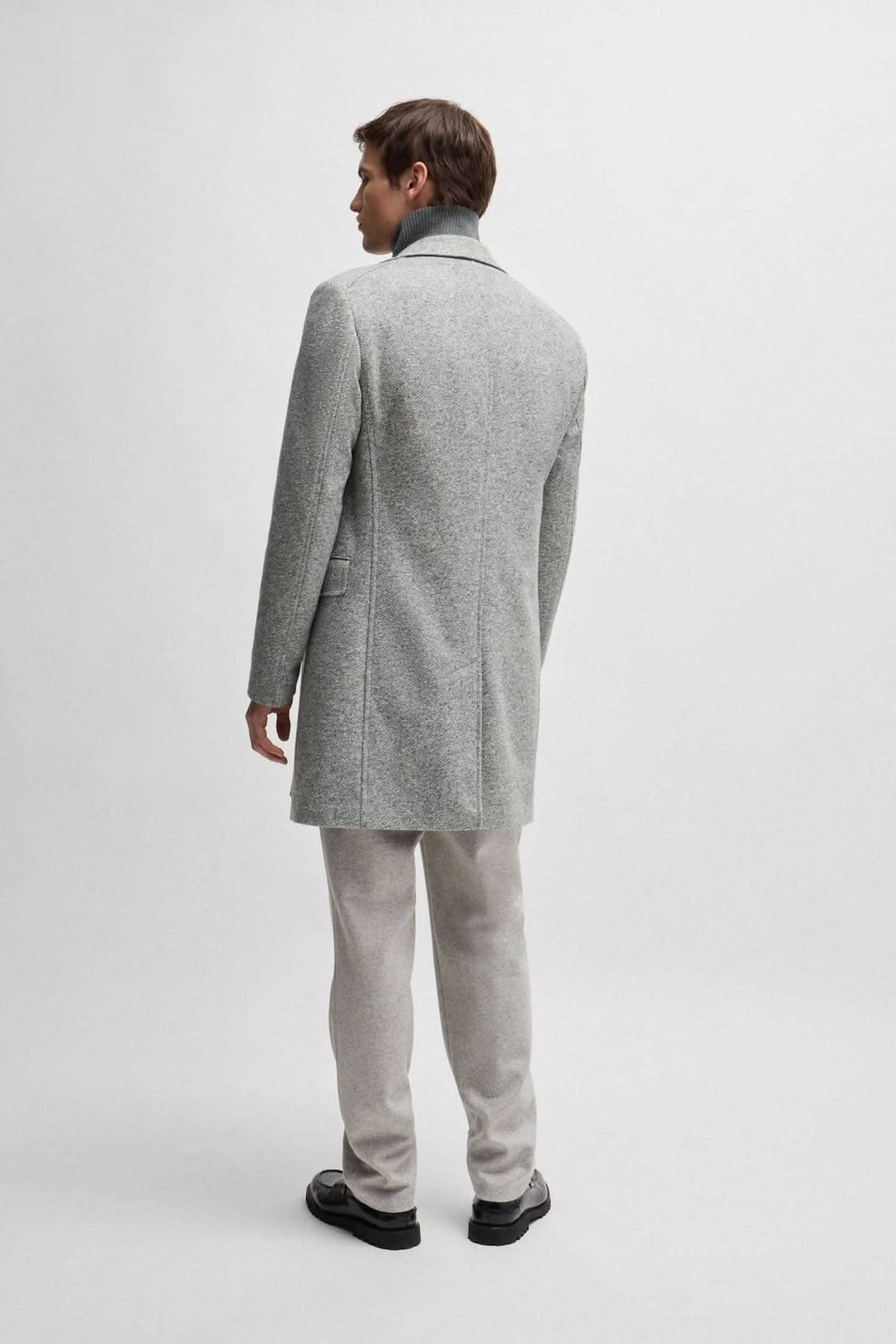 Homme portant un manteau à chevrons gris avec une coupe ajustée, vu de dos.