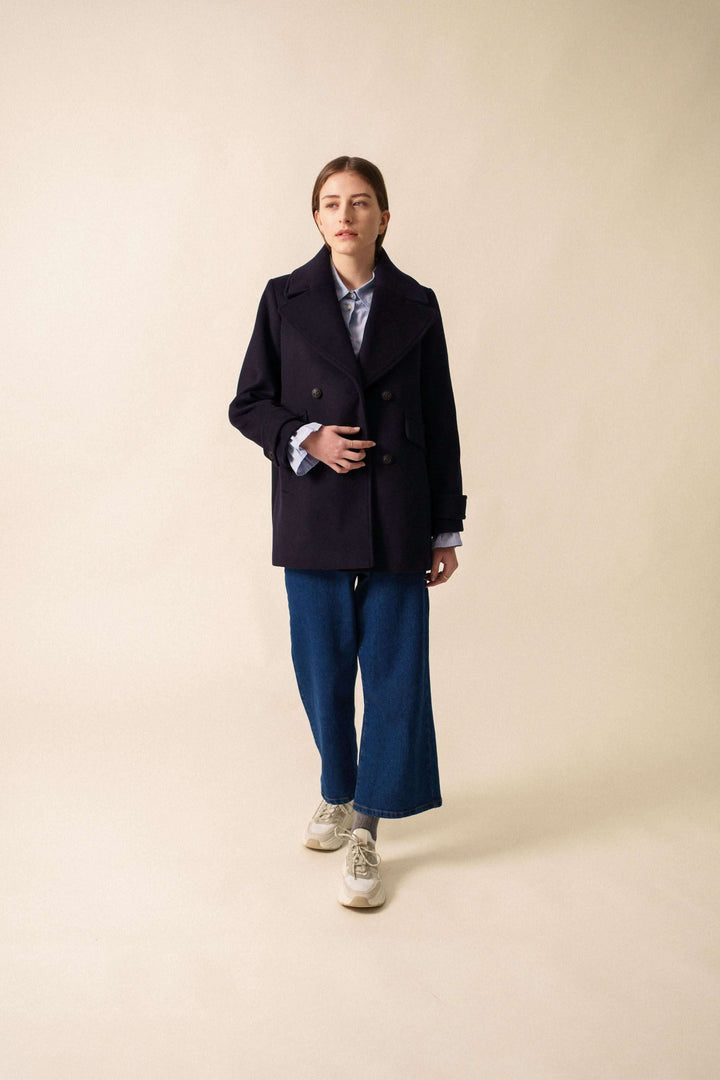 Manteau chic STE ROMY avec col en V, grand col et quatre boutons, porté sur chemise pour look décontracté.