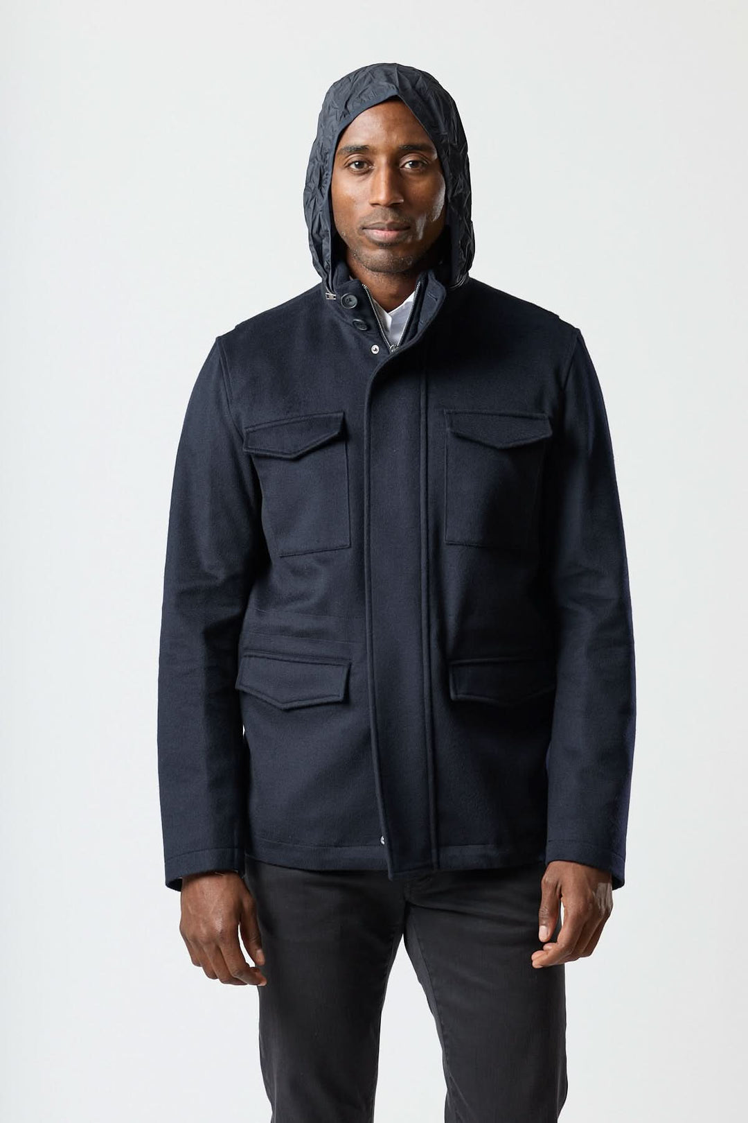 Homme portant un manteau en laine à quatre poches avec capuche légère, style veston de campagne, idéal pour un look smart-casual.