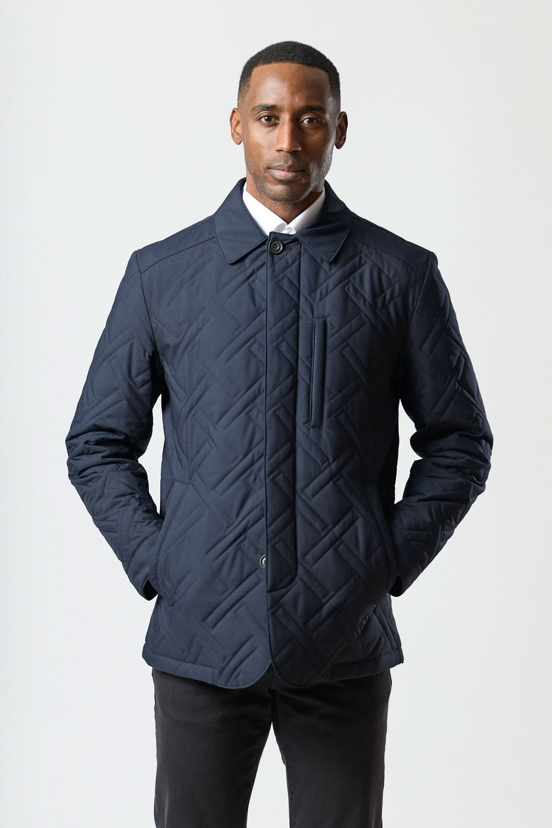 Homme portant un manteau matelassé technique marine avec motif géométrique élégant et tissu déperlant pour un style quotidien performant.