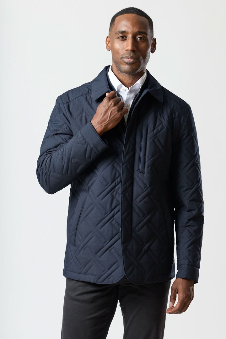 Homme portant un manteau matelassé technique marine avec motif géométrique, parfait pour le confort et la performance quotidienne.