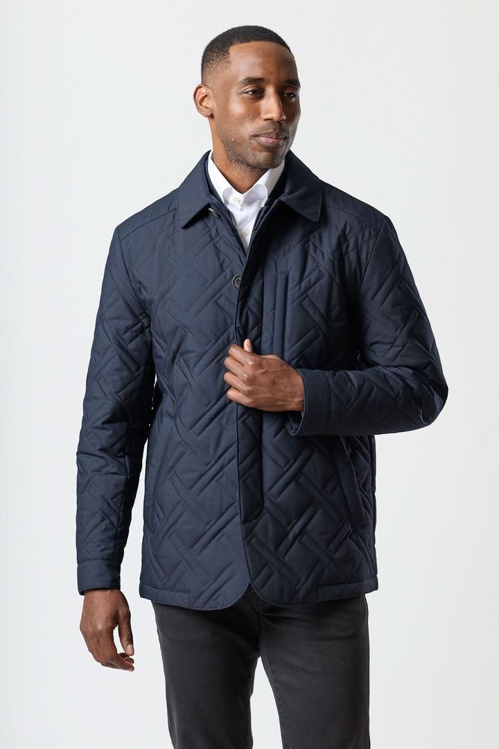 Homme portant un manteau matelassé technique marine Corneliani, élégant et déperlant avec motif géométrique et coupe fluide.