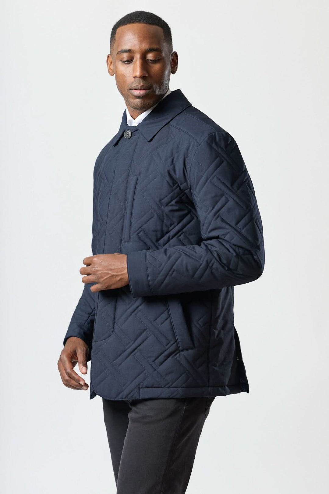 Homme portant un manteau matelassé technique marine élégant, design Corneliani avec motif géométrique et tissu déperlant.