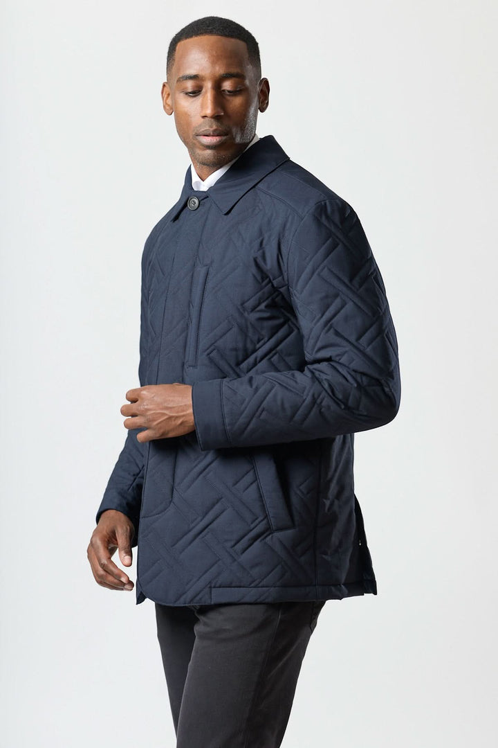 Homme portant un manteau matelassé technique marine élégant, design Corneliani avec motif géométrique et tissu déperlant.
