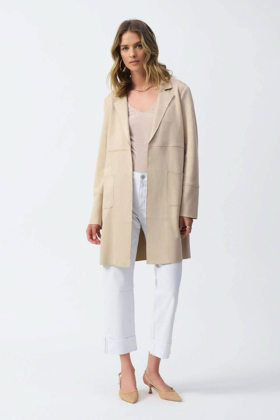 Manteau mi-long crème avec col cranté, porté sur un haut clair et un pantalon blanc, offrant une allure élégante.