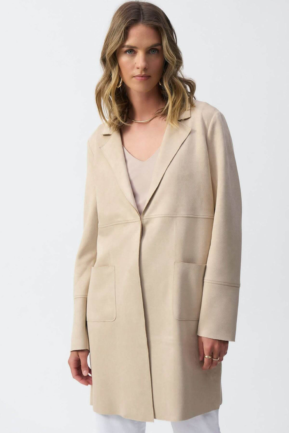 Manteau mi-long beige à texture veloutée, col cranté, manches longues et poches avant, style minimaliste.