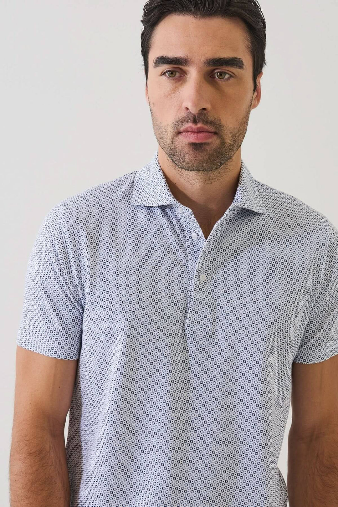 Homme portant un POLO IMPRIMÉ À MANCHES COURTES avec un motif géométrique discret et un col ouvert, idéal pour l&