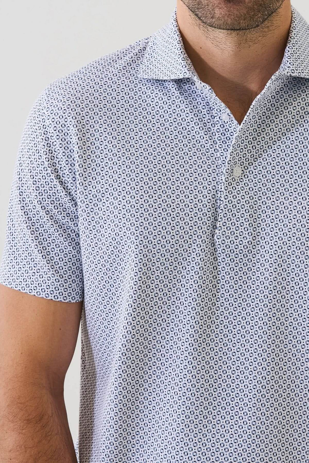 Homme portant un POLO IMPRIMÉ À MANCHES COURTES avec un motif géométrique subtil et tissu extensible, couleur discrète et élégante.