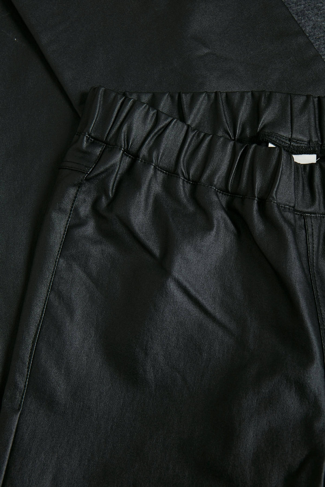 Détails du pantalon Ada en simili cuir noir avec une taille élastique pour un look moderne et sophistiqué.